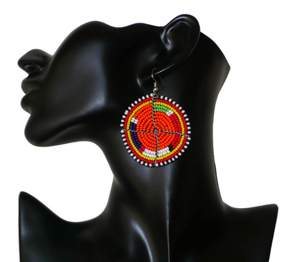 Boucles d'oreilles africaines traditionnelles Massai faites de perles de rocaille orange et multicolores glissées sur des structures circulaires en fils de fer. Elles mesurent 6,5 cm de long et 5 cm de large, et se portent avec des attaches en acier inoxydable sur des oreilles percées.