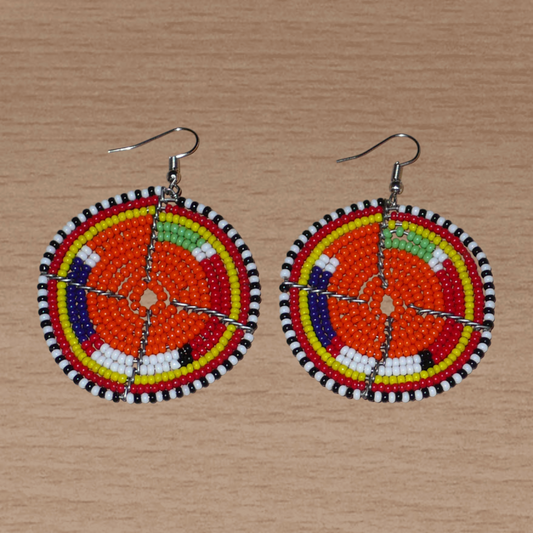 Boucles d'oreilles africaines traditionnelles Massai faites de perles de rocaille orange et multicolores glissées sur des structures rondes en fils de fer. Elles mesurent 6,5 cm de long et 5 cm de large, et se portent avec des crochets en acier inoxydable sur des oreilles percées.