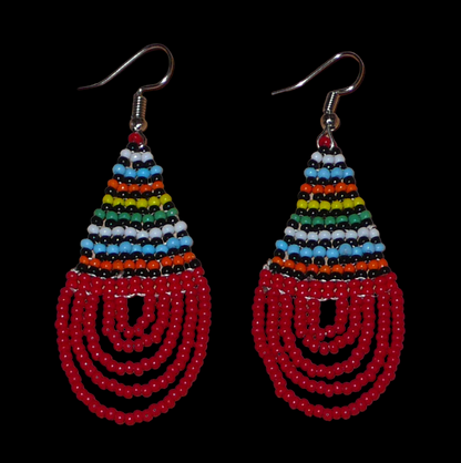 Boucles d'oreilles africaines rouges et multicolores en forme de gouttes. Elles mesurent 7 cm de long et 2,5 cm de large, et se portent sur des oreilles percées.