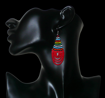 Boucles d'oreilles africaines rouges et multicolores en forme de gouttes. Elles mesurent 7 cm de long et 2,5 cm de large, et se portent sur des oreilles percées.
