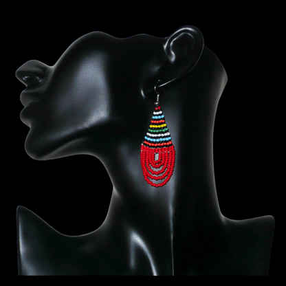 Boucles d'oreilles africaines rouges et multicolores en forme de gouttes. Elles mesurent 7 cm de long et 2,5 cm de large, et se portent sur des oreilles percées.