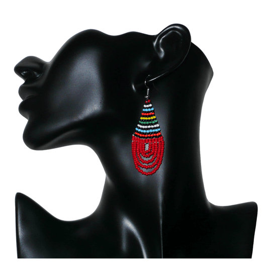 Boucles d'oreilles africaines rouges et multicolores en forme de gouttes. Elles mesurent 7 cm de long et 2,5 cm de large, et se portent sur des oreilles percées.