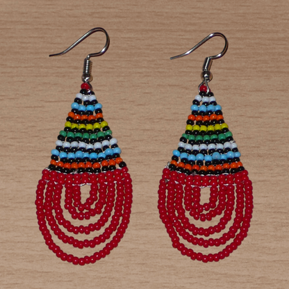 Boucles d'oreilles africaines rouges et multicolores en forme de gouttes. Elles mesurent 7 cm de long et 2,5 cm de large, et se portent sur des oreilles percées.