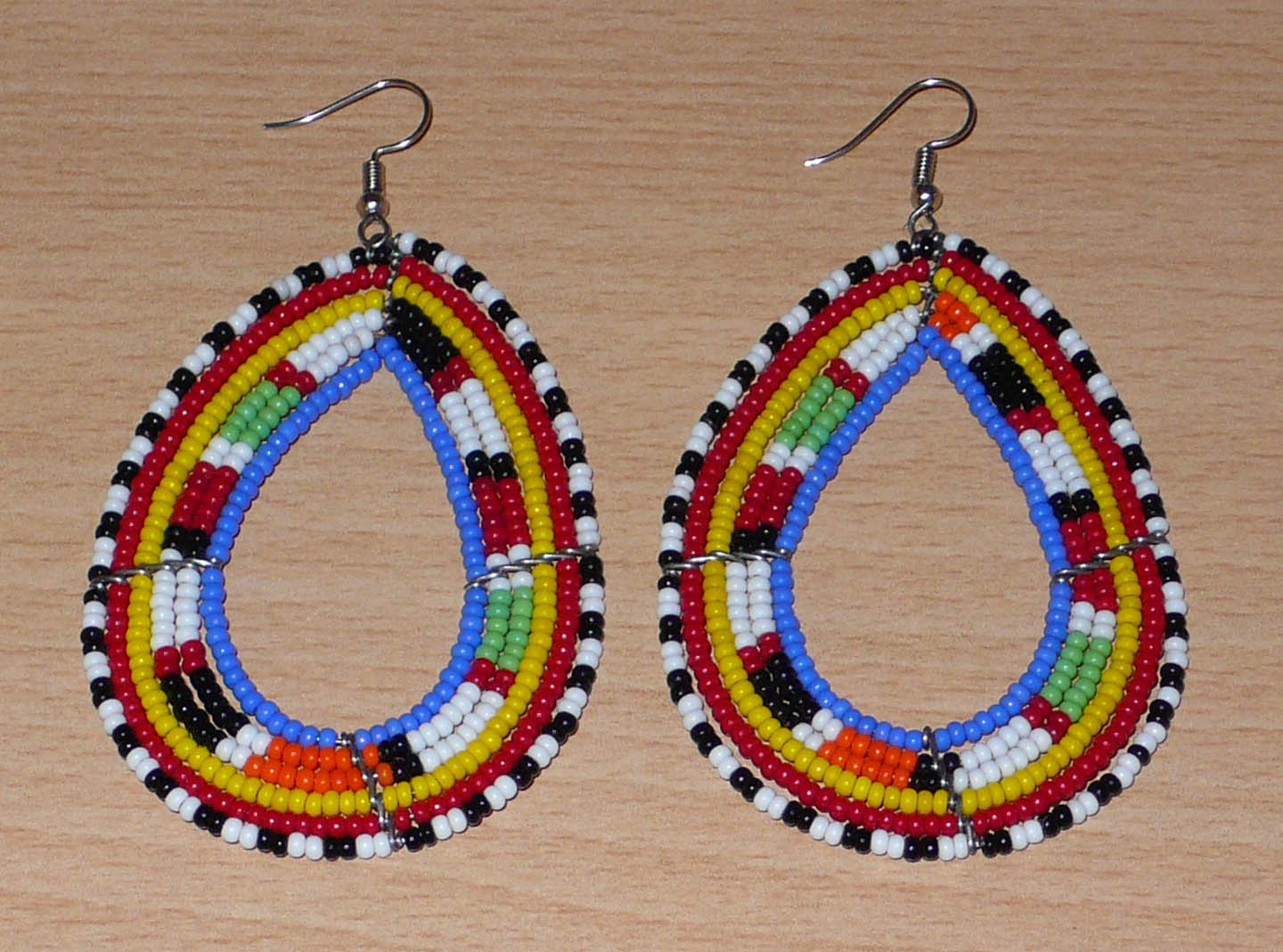 Longues boucles d'oreilles Massai traditionnelles composées de perles de rocaille bleues et multicolores montées en forme de gouttes. Elles mesurent 9 cm de long et 5 cm de large et se portent sur des oreilles percées.