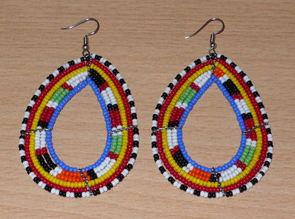 Longues boucles d'oreilles Massai traditionnelles composées de perles de rocaille bleues et multicolores montées en forme de gouttes. Elles mesurent 9 cm de long et 5 cm de large et se portent sur des oreilles percées.