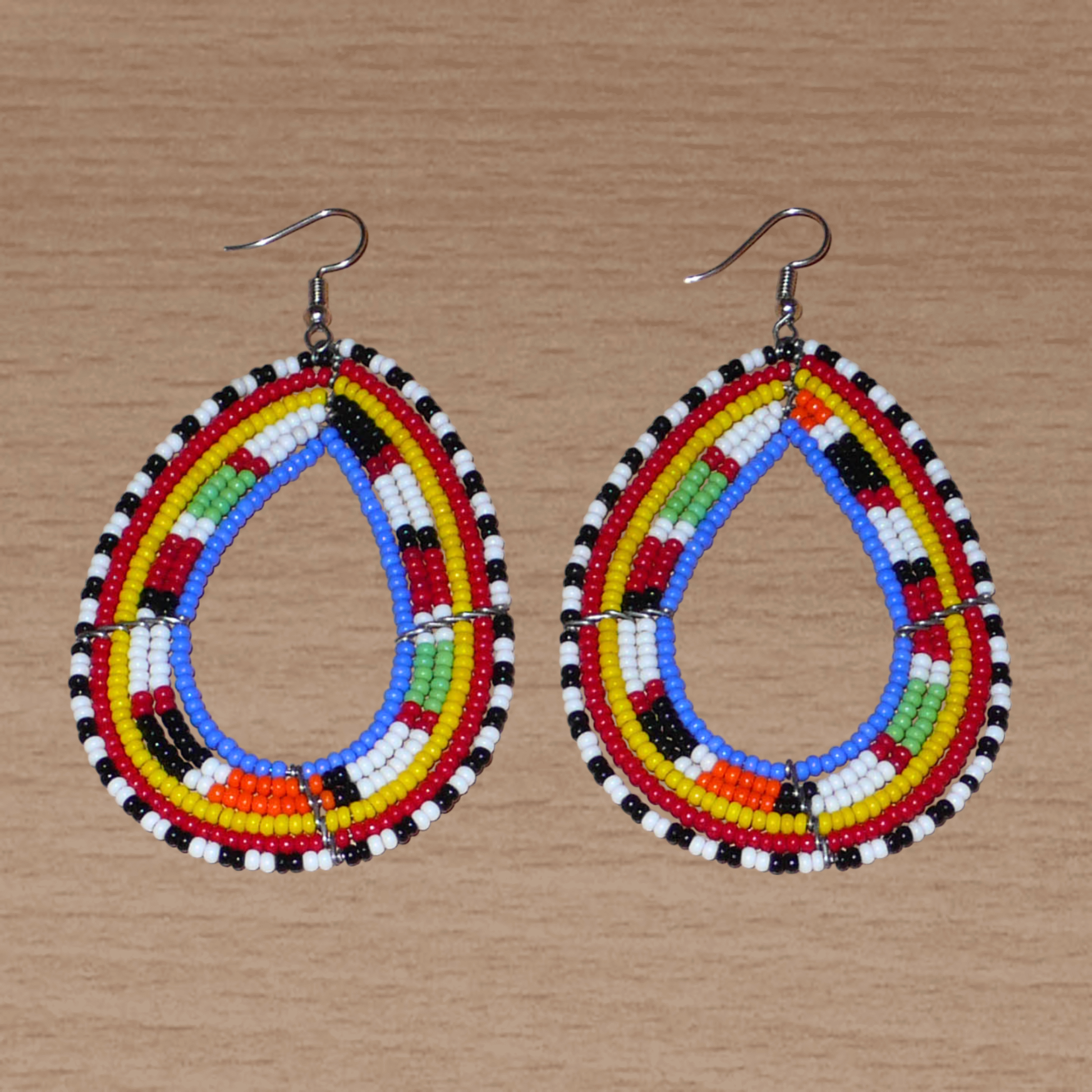 Longues boucles d'oreilles Massai traditionnelles composées de perles de rocaille bleues et multicolores montées en forme de gouttes. Elles mesurent 9 cm de long et 5 cm de large et se portent sur des oreilles percées.