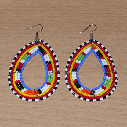 Longues boucles d'oreilles Massai traditionnelles composées de perles de rocaille bleues et multicolores montées en forme de gouttes. Elles mesurent 9 cm de long et 5 cm de large et se portent sur des oreilles percées.