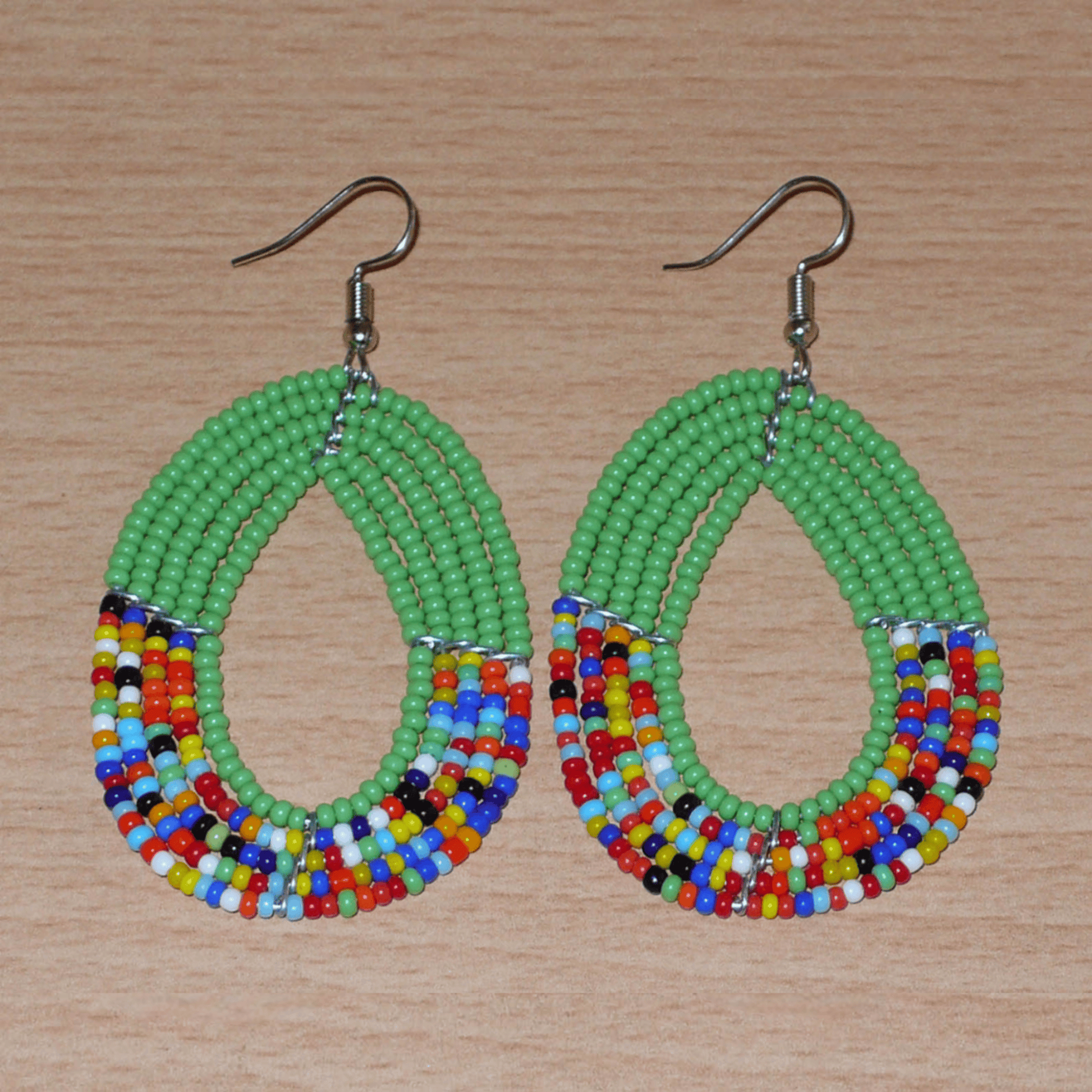 Boucles d'oreilles kenyanes multi-rangs vertes et multicolores en forme de gouttes. Elles mesurent 7 cm de long et 4 cm de large et se portent avec des crochets sur des oreilles percées.