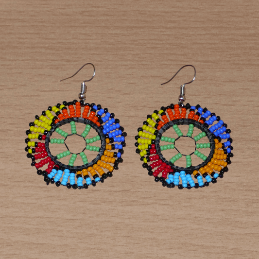 Boucles d'oreilles ethniques rondes à motifs zoulous composées de perles de rocaille vertes et multicolores. De taille moyenne et légères à porter, elles mesurent 6 cm de long et 4 cm de large ; elles se portent avec des crochets en acier inoxydable sur des oreilles percées.