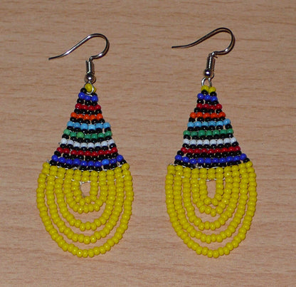 Boucles d'oreilles ethniques jaunes et multicolores composées d'un tissage en forme de gouttes de perles de rocaille. De taille moyenne et légère à porter, elles mesurent 7 cm de long et 2,5 cm de large et se portent avec des crochets en acier inoxydable sur des oreilles percées.