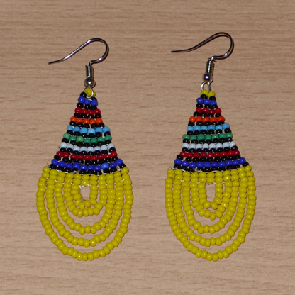 Boucles d'oreilles ethniques jaunes et multicolores composées d'un tissage en forme de gouttes de perles de rocaille. De taille moyenne et légère à porter, elles mesurent 7 cm de long et 2,5 cm de large et se portent avec des crochets en acier inoxydable sur des oreilles percées.