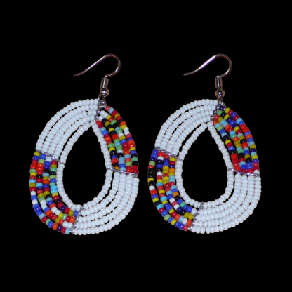 Boucles d'oreilles exotiques multi-rangs en forme de gouttes composées de perles de rocaille blanches et multicolores. De taille moyenne, elles mesurent 7 cm de long et 4 cm de large, et se portent sur des oreilles percées.