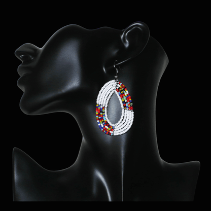 Boucles d'oreilles exotiques multi-rangs en forme de gouttes composées de perles de rocaille blanches et multicolores. De taille moyenne, elles mesurent 7 cm de long et 4 cm de large, et se portent sur des oreilles percées.