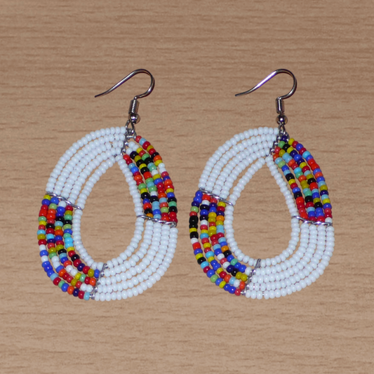 Boucles d'oreilles exotiques multi-rangs en forme de gouttes composées de perles de rocaille blanches et multicolores. De taille moyenne, elles mesurent 7 cm de long et 4 cm de large, et se portent sur des oreilles percées.