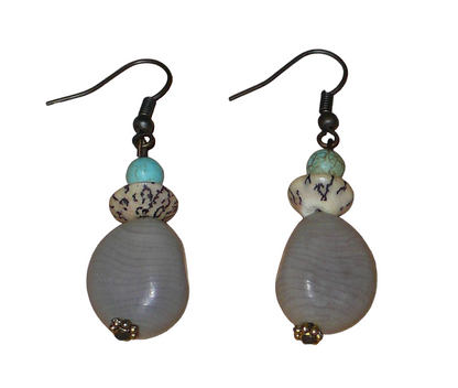 Boucles d'oreilles exotiques composées de perles et de graines de caniques grises. De taille moyenne, elles mesurent 5 cm de long et 1,5 cm de large, et se portent sur des oreilles percées.