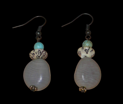 Boucles d'oreilles exotiques composées de perles et de graines de caniques grises. De taille moyenne, elles mesurent 5 cm de long et 1,5 cm de large, et se portent sur des oreilles percées.