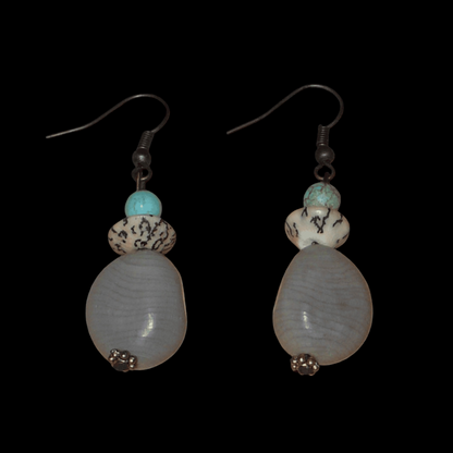 Boucles d'oreilles exotiques composées de perles et de graines de caniques grises. De taille moyenne, elles mesurent 5 cm de long et 1,5 cm de large, et se portent sur des oreilles percées.