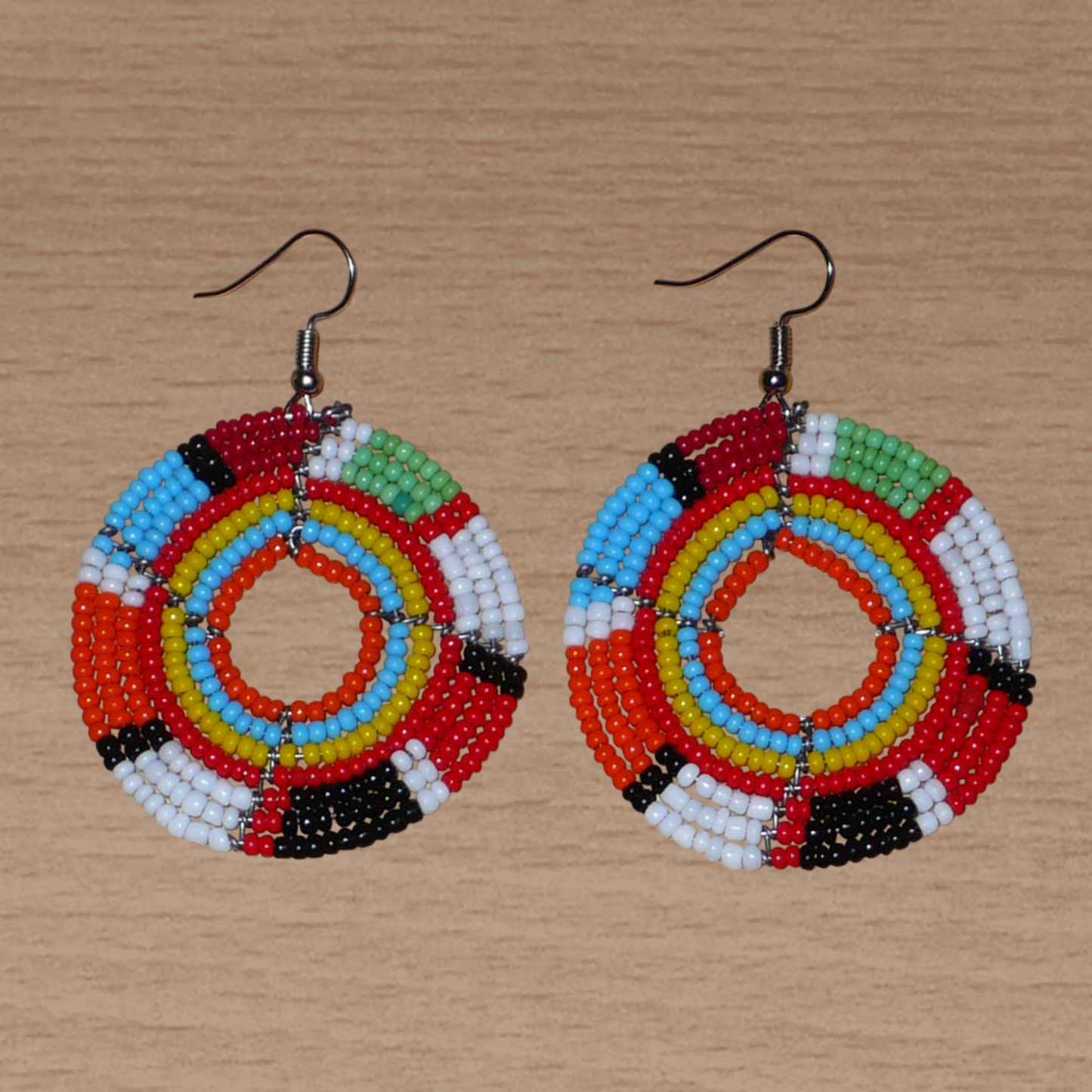 Boucles d'oreilles exotiques rondes aux couleurs rétro évoquant les années 70 composées de perles de rocaille multicolores. Elles mesurent 6.5 cm de long et 4.5 cm de large, et se portent sur des oreilles percées.