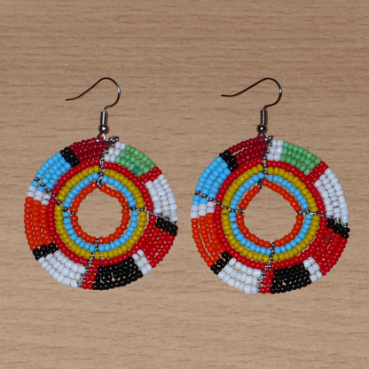Boucles d'oreilles exotiques rondes aux couleurs rétro évoquant les années 70 composées de perles de rocaille multicolores. Elles mesurent 6.5 cm de long et 4.5 cm de large, et se portent sur des oreilles percées.
