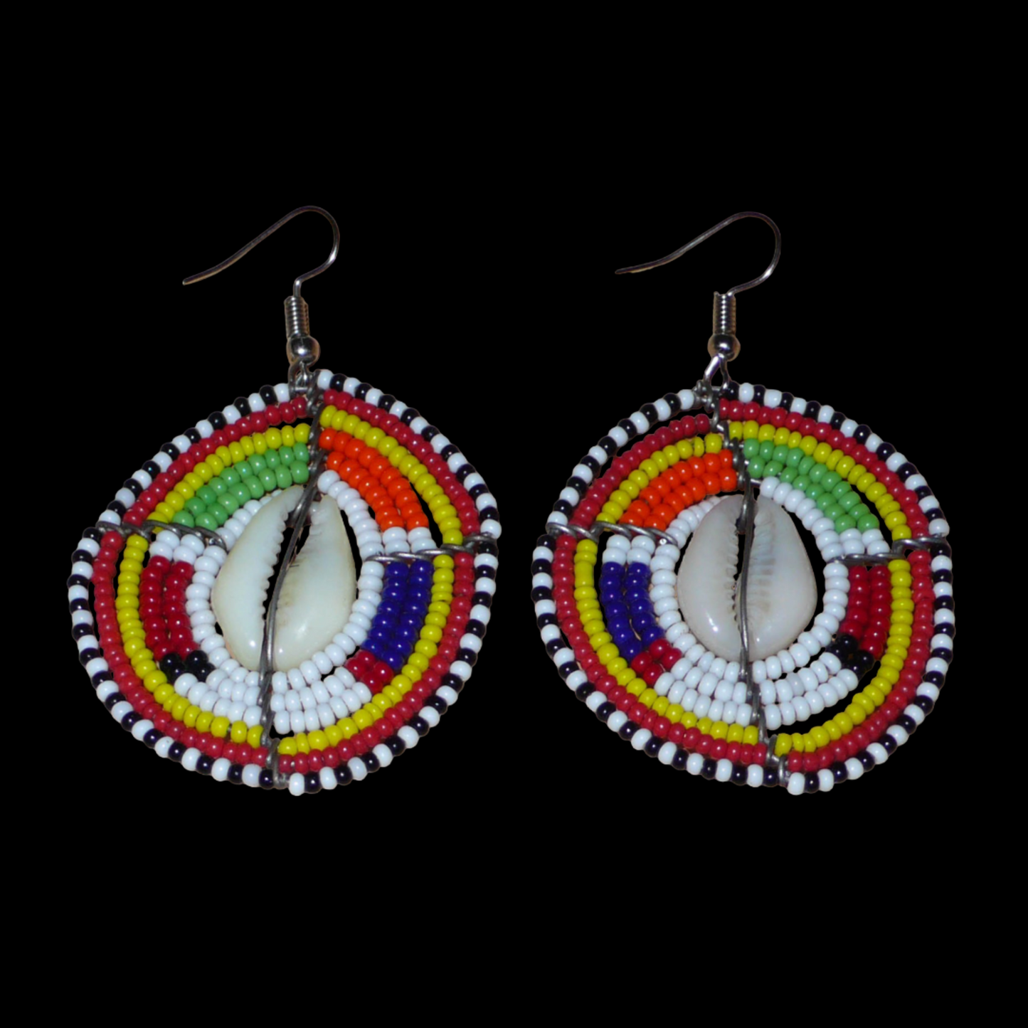 Ambiance traditionnelle Massai avec ce modèle de boucles d'oreilles africaines aux couleurs exotiques et motifs ethniques ! De fabrication tribale artisanale kenyane, elles sont composées de perles de rocaille blanches et multicolores et de coquillages fixés sur des fils de fer montés en forme de boucliers Massai. Ces boucles d'oreilles de taille moyenne mesurent 6.5 cm de long et 4 cm de large, et se portent avec des crochets en acier inoxydable sur des oreilles percées.