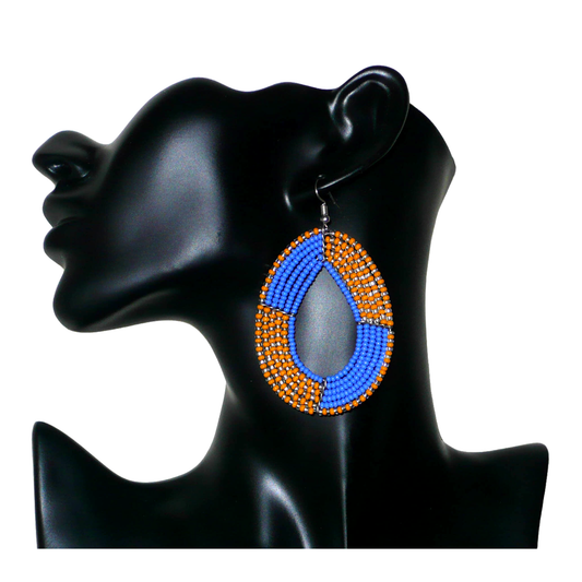 Boucles d'oreilles kenyanes multi-rangs en perles de rocaille bleues, orange et gris nacré. Elles mesurent 8 cm de long et 5 cm de large et se portent sur des oreilles percées.