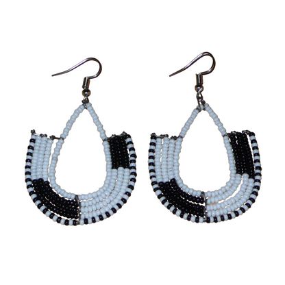 Ajoutez une touche ethnique contemporaine à votre tenue avec cette paire de boucles d'oreilles africaines bicolores blanches et noires ! De fabrication artisanale kenyane, elles se composent de perles de rocaille blanches et noires glissées sur des structures en fils de fer montés en forme d'ancres. Ces boucles d'oreilles mesurent 7 cm de long et 4 cm de large, et se portent avec des crochets en acier inoxydable sur des oreilles percées.