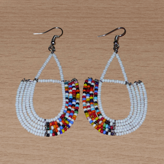 Longues boucles d'oreilles ethniques en forme d'ancres composées de perles de rocaille blanches et d'un mélange de perles multicolores. Ces boucles d'oreilles à l'esprit bohème mesurent 8 cm de long et 4 cm de large et se portent sur des oreilles percées.