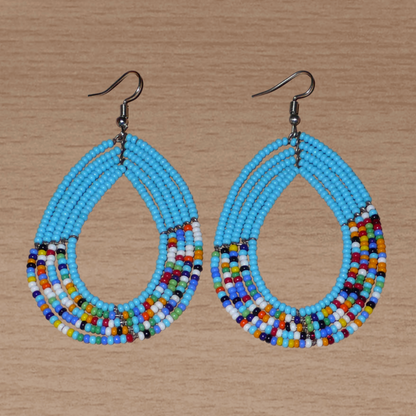 Boucles d'oreilles kenyanes en perles de rocaille bleu ciel et multicolores montées en forme de gouttes. Elles mesurent 8 cm de long et 4.5 cm de large, et se portent sur des oreilles percées.