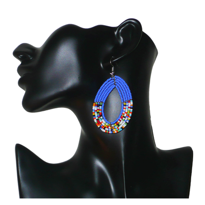 Boucles d'oreilles kenyanes multi-rangs de forme ovales, en perles de rocaille bleues et multicolores. Elles mesurent 7.5 cm de long et 4 cm de large et se portent sur des oreilles percées.