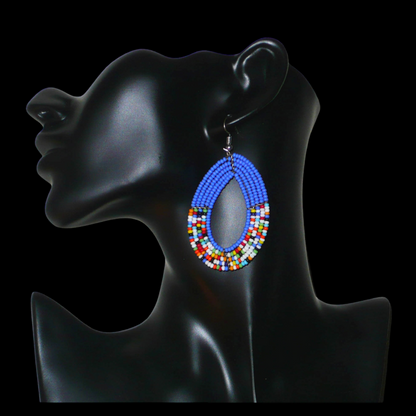 Boucles d'oreilles kenyanes multi-rangs de forme ovales, en perles de rocaille bleues et multicolores. Elles mesurent 7.5 cm de long et 4 cm de large et se portent sur des oreilles percées.