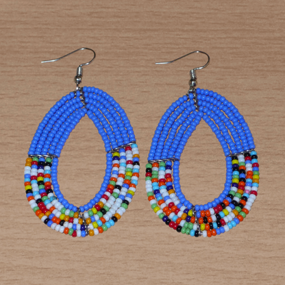 Boucles d'oreilles kenyanes multi-rangs de forme ovales, en perles de rocaille bleues et multicolores. Elles mesurent 7.5 cm de long et 4 cm de large et se portent sur des oreilles percées.