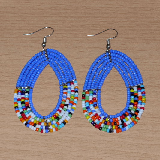 Boucles d'oreilles kenyanes multi-rangs de forme ovales, en perles de rocaille bleues et multicolores. Elles mesurent 7.5 cm de long et 4 cm de large et se portent sur des oreilles percées.