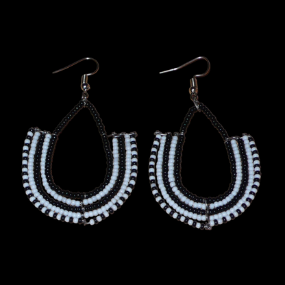 Boucles d'oreilles kenyanes Massai bicolores en forme d'ancres composées de perles de rocaille noires et blanches glissées sur des structures géométriques en fils de fer. De taille moyenne, ces boucles d'oreilles aux accents ethniques afro chic mesurent 7 cm de long et 4 cm de large ; elles se portent avec des crochets en acier inoxydable sur des oreilles percées.