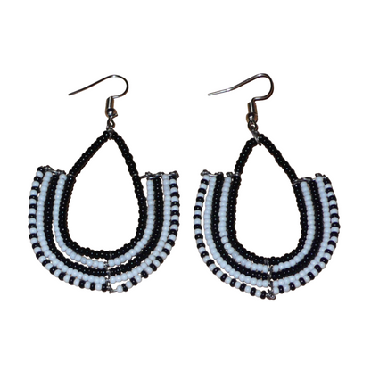 Boucles d'oreilles kenyanes Massai bicolores en forme d'ancres composées de perles de rocaille noires et blanches glissées sur des structures géométriques en fils de fer. De taille moyenne, ces boucles d'oreilles aux accents ethniques afro chic mesurent 7 cm de long et 4 cm de large ; elles se portent avec des crochets en acier inoxydable sur des oreilles percées.