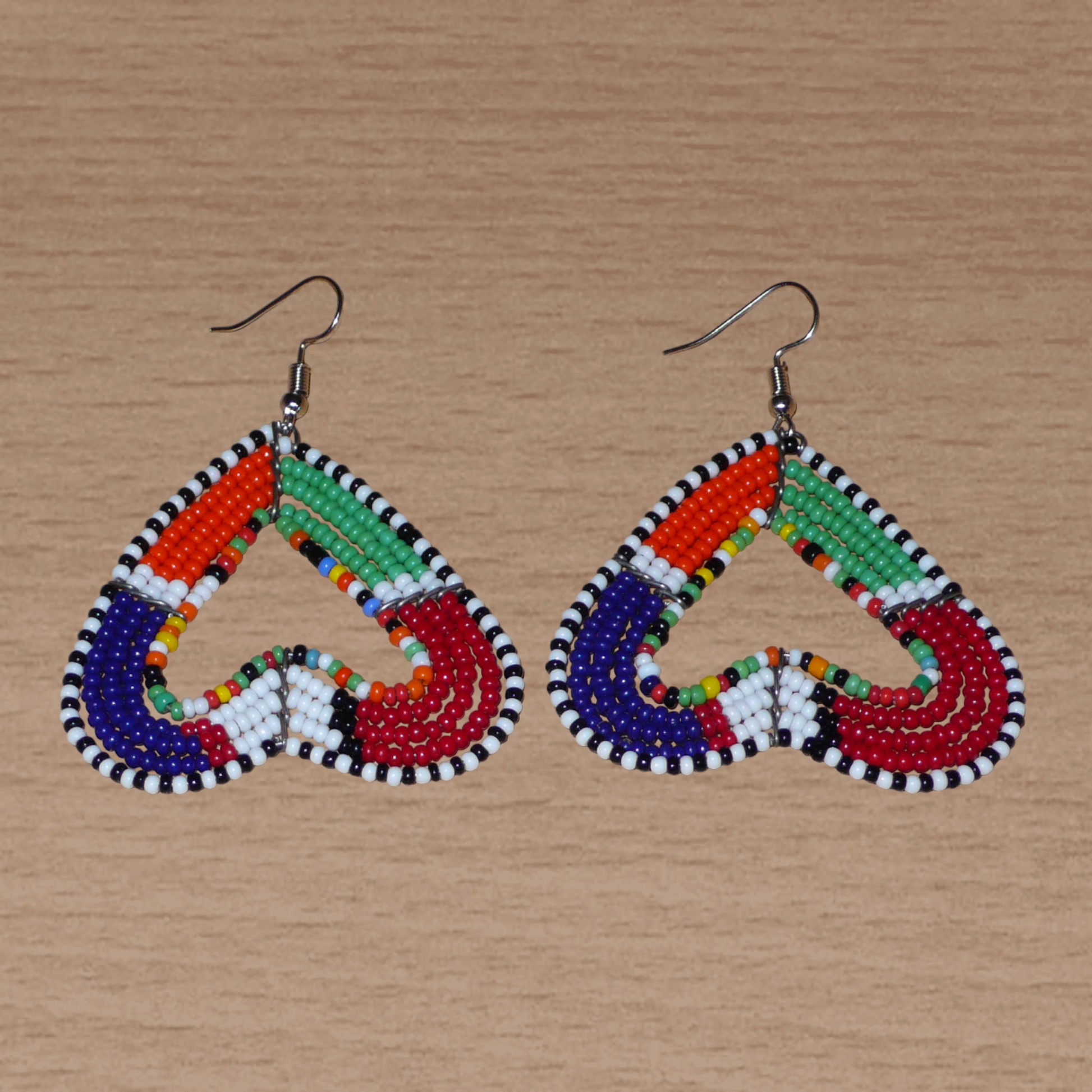 Boucles d'oreilles kenyanes Massai de fabrication artisanale se composant de perles de rocaille multicolores glissées sur cinq rangées de fils de fer montés en forme de cœurs inversés.

Cette paire de boucles d'oreilles de taille moyenne mesure 6.5 cm de long et 5 cm de large ; elle se porte avec des crochets en acier inoxydable sur des oreilles percées.