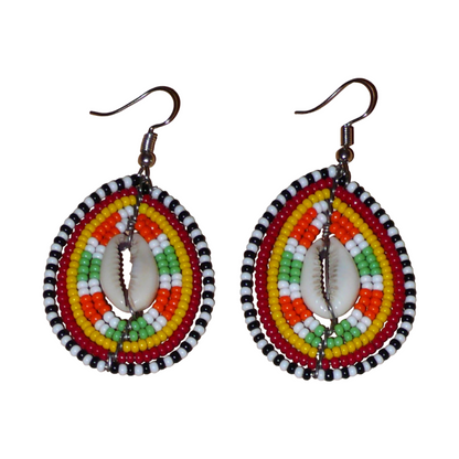 Boucles d'oreilles kenyanes à motifs ethniques en forme de boucliers Massai ; elles se composent de perles et de coquillages cauris, et mesurent 7 cm de long et 4 cm de large, elles se portent sur des oreilles percées.