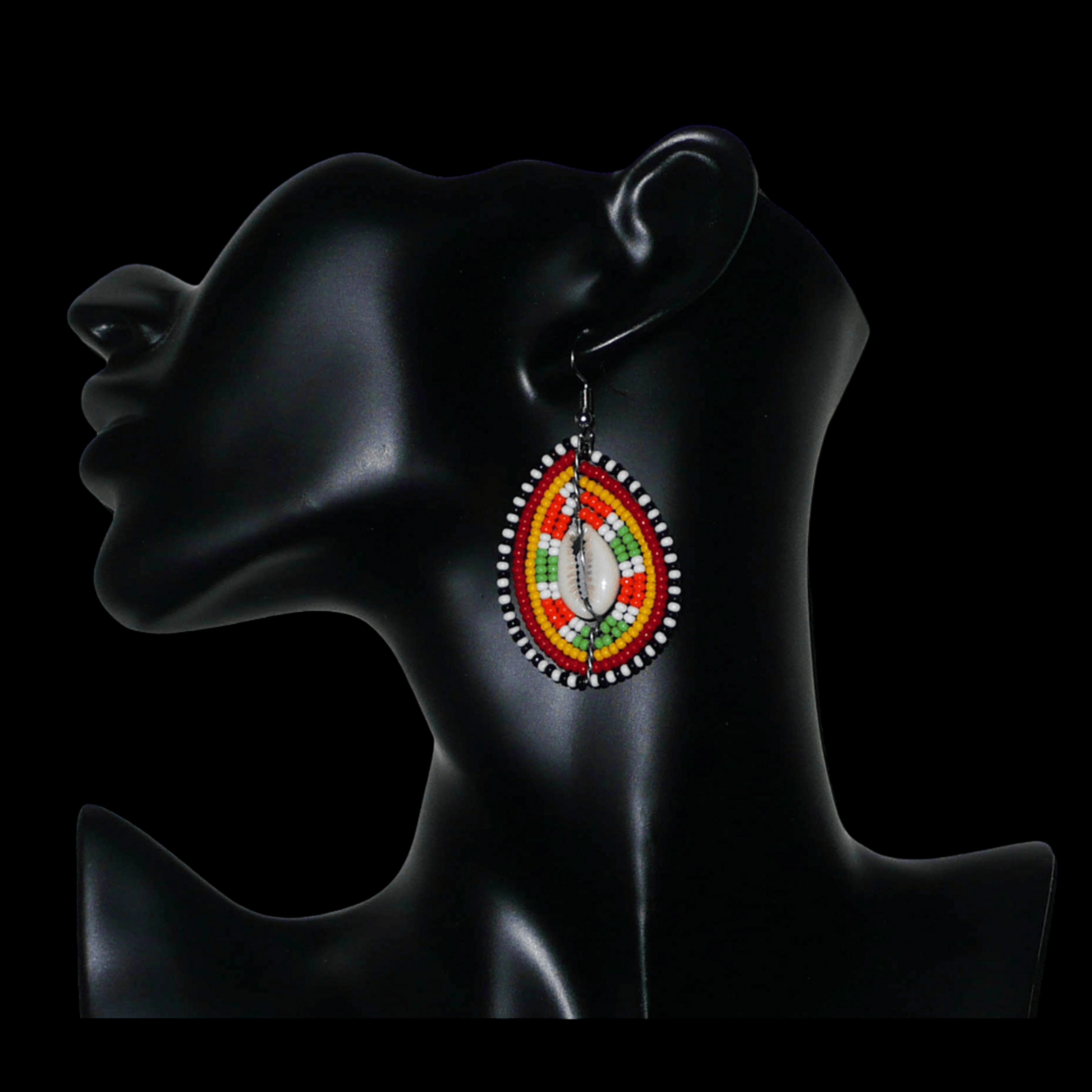 Boucles d'oreilles kenyanes à motifs ethniques en forme de boucliers Massai ; elles se composent de perles et de coquillages cauris, et mesurent 7 cm de long et 4 cm de large, elles se portent sur des oreilles percées.