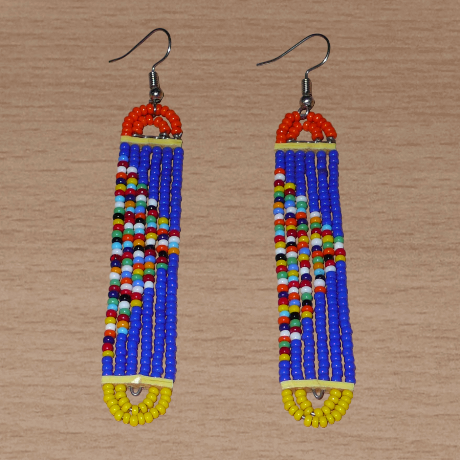 Longues boucles d'oreilles kenyanes en perles de rocaille bleues, orange, jaunes et multicolores glissées sur six rangées de fils de fer montés en forme de rectangles aux bouts arrondis. Elles mesurent 9,5 cm de long et 1,5 cm de large et se portent sur des oreilles percées.