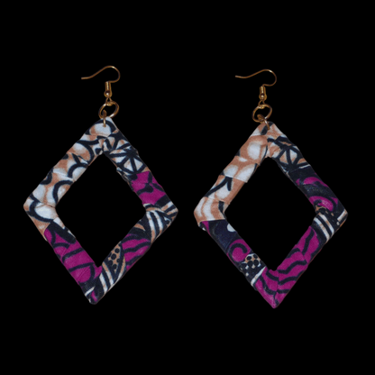 Longues boucles d'oreilles africaines en forme de losanges composées de tissu africain rose-violet, avec des touches de noir, de blanc et de beige. Elles mesurent 11 cm de long et 6 cm de large et se portent sur des oreilles percées.