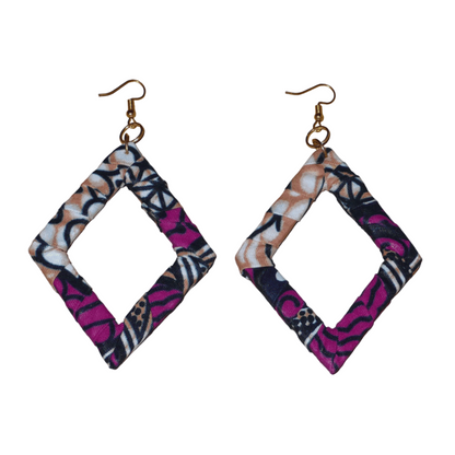 Longues boucles d'oreilles africaines en forme de losanges composées de tissu africain rose-violet, avec des touches de noir, de blanc et de beige. Elles mesurent 11 cm de long et 6 cm de large et se portent sur des oreilles percées.