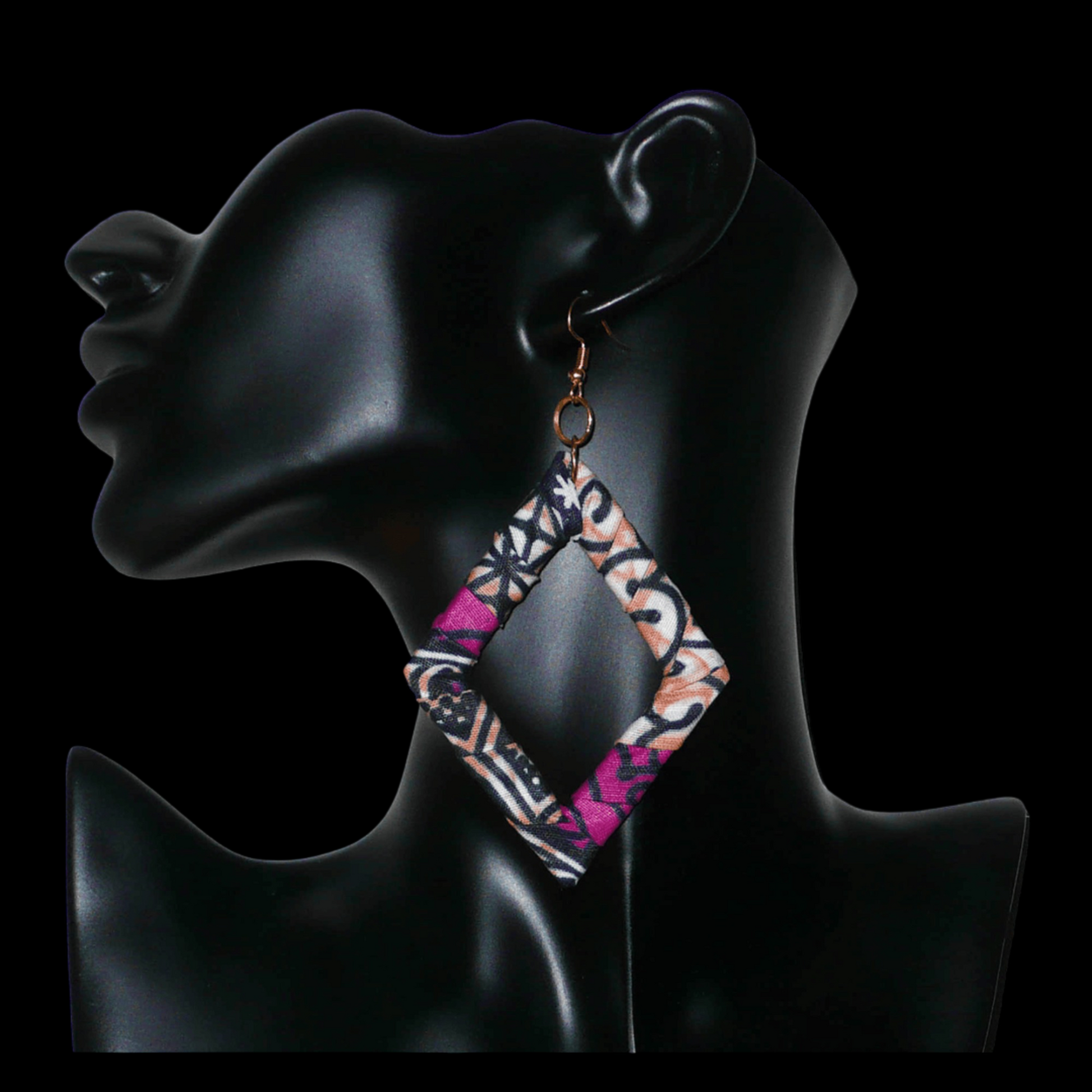 Longues boucles d'oreilles africaines en forme de losanges composées de tissu africain rose-violet, avec des touches de noir, de blanc et de beige. Elles mesurent 11 cm de long et 6 cm de large et se portent sur des oreilles percées.