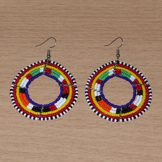 Boucles d'oreilles africaines rondes à motifs ethniques Massai faites de perles bleu foncé et multicolores. Elles mesurent 7 cm de long et 5 cm de large et se portent avec des crochets en acier inoxydable sur des oreilles percées.