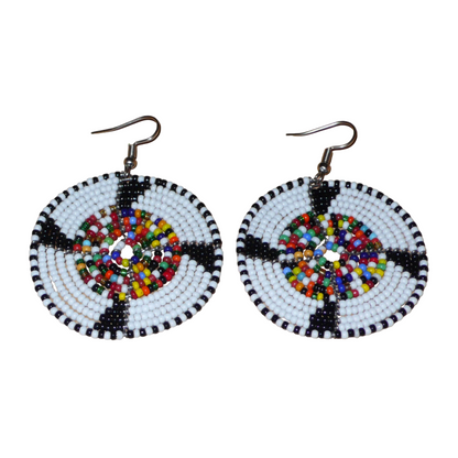 Ajoutez une touche ethnique à votre style avec ces boucles d'oreilles africaines rondes confectionnées dans la tradition artisanale Massai. Elles se composent de perles de rocaille principalement blanches, puis noires et multicolores glissées sur des structures circulaires en fils de fer. Cette paire de boucles d'oreilles mesure 6.5 cm de long et 4.5 cm de large, et se porte avec des crochets en acier inoxydable sur des oreilles percées.