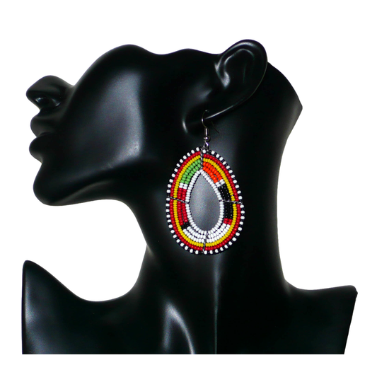 Boucles d'oreilles Massai multi-rangs blanches et multicolores faites de perles de rocaille montées en forme de gouttes. Elles mesurent 7. cm de long et 4 cm de large, et se portent sur des oreilles percées.