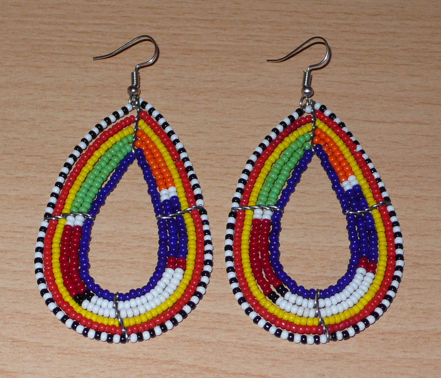 Boucles d'oreilles africaines Massai bleu marine et multicolores en forme de gouttes. Elles mesurent 8.5 cm de long et se portent sur des oreilles percées.