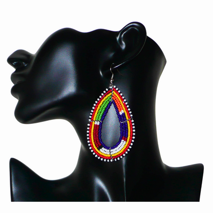 Boucles d'oreilles africaines Massai bleu marine et multicolores en forme de gouttes. Elles mesurent 8.5 cm de long et se portent sur des oreilles percées.
