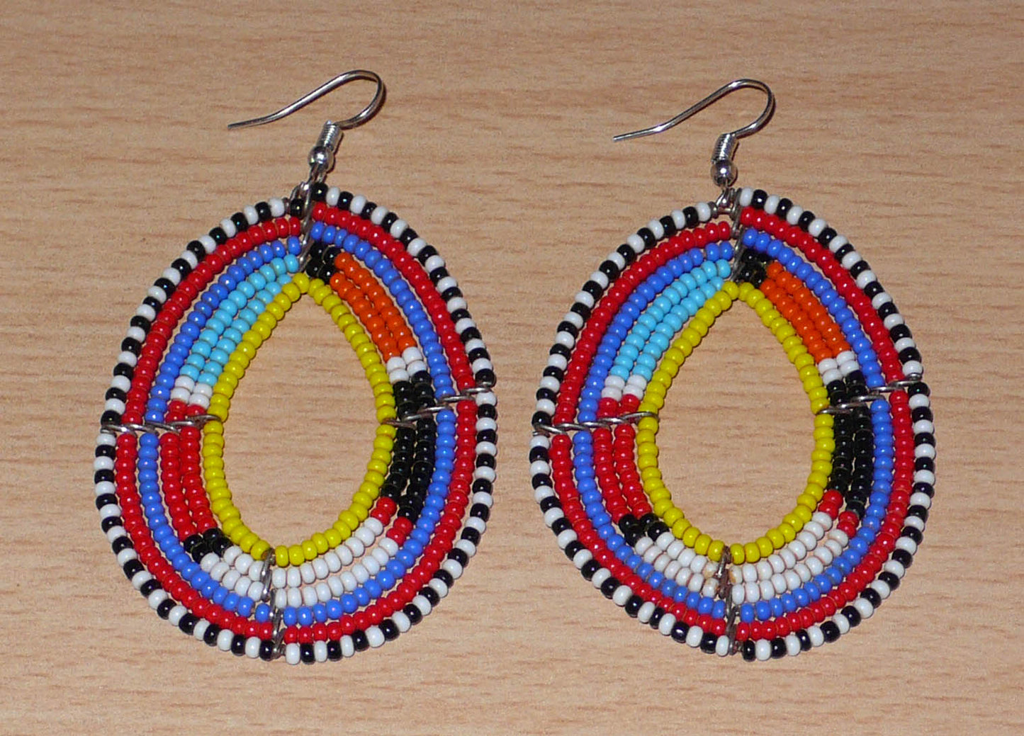 Boucles d'oreilles ethniques Massai faites de perles de rocaille multicolores montées en forme de gouttes. Elles mesurent 8 cm de long et 4.5 cm de large et se portent sur des oreilles percées.