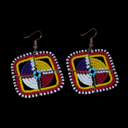 Boucles d'oreilles africaines de tradition ethnique Massai composées de perles de rocaille multicolores enfilées sur des structures géométriques en fils de fer. Ces boucles d'oreilles colorées aux accents exotiques mesurent 5.5 cm de long et 4.5 cm de large ; elles se portent avec des crochets en acier inoxydable sur des oreilles percées.