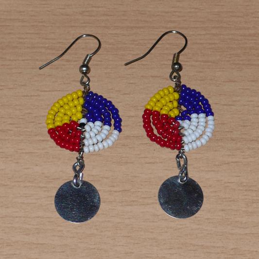 Boucles d'oreilles Massai rondes à quatre couleurs, composées de perles de rocaille bleu foncé, rouges, jaunes et blanches montées en forme de petits disques et décorées de pastilles métalliques. Elles mesurent 6 cm de long et 2 cm de large, et se portent sur des oreilles percées.