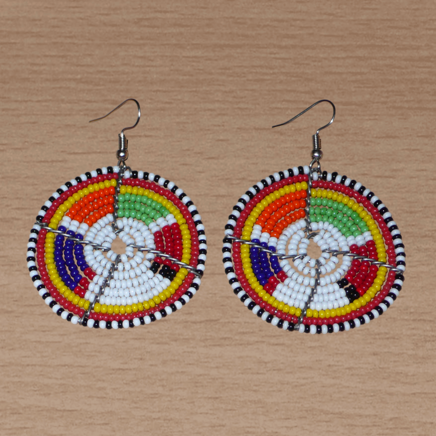 Boucles d'oreilles africaines de tradition tribale Massai composées de perles de rocaille blanches et multicolores montées en forme de disques. Elles mesurent 6.5 cm de long et 4.5 cm de large et se portent sur des oreilles percées.